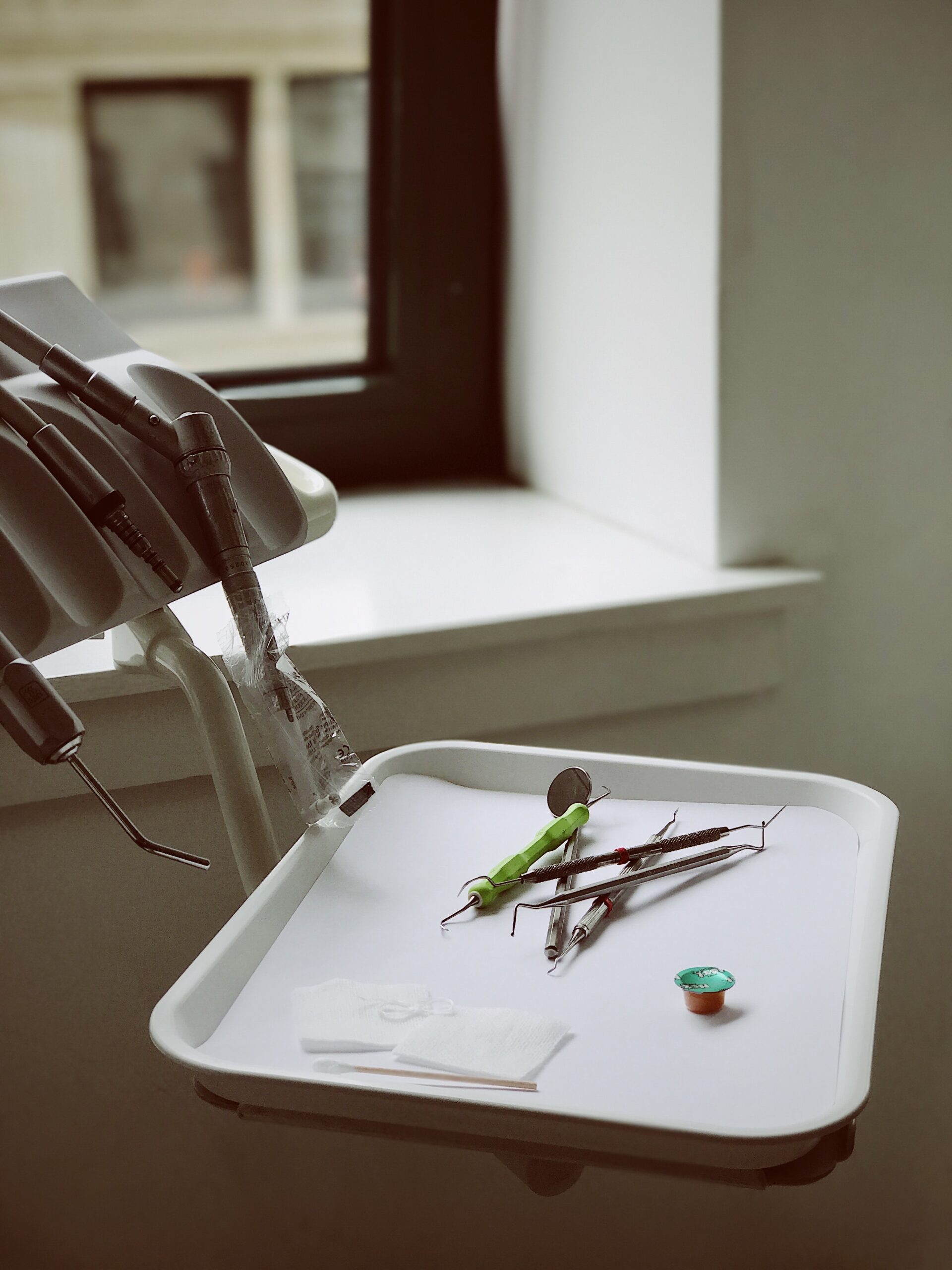 Dental equipment arranged on a tray beside a dentist's chair in a Texas dentistry office, with a window in the background.