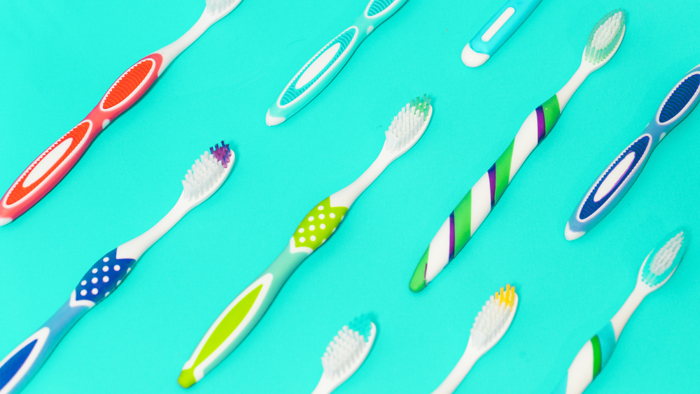 Colorful toothbrushes arranged in a pattern on a turquoise background at a Texas dentistry clinic.