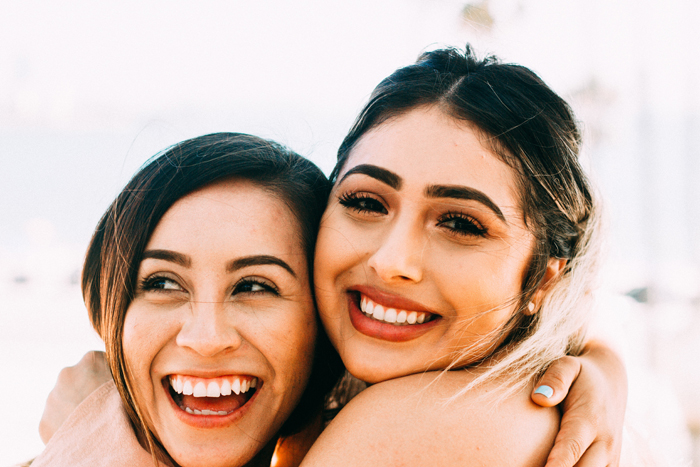 Two smiling women embracing each other at a Texas dentistry event.
