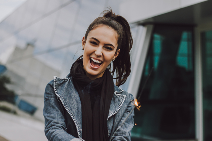 A joyful woman laughing in an affordable Dallas dentist's urban setting.