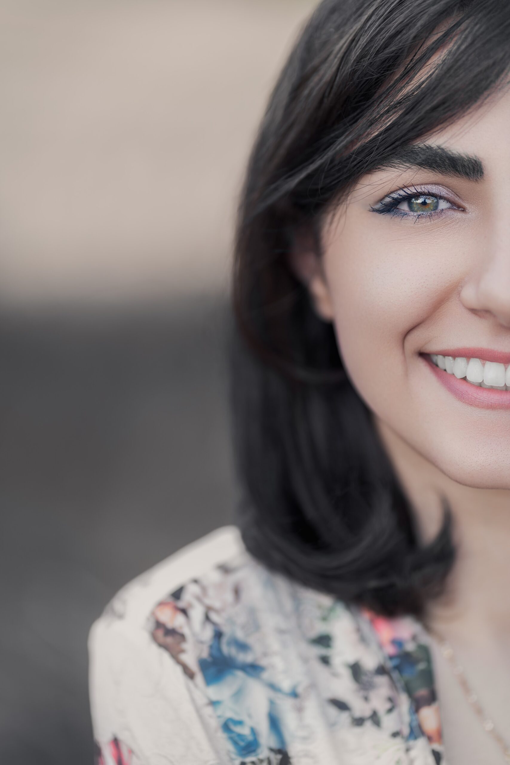 Close-up of a smiling woman with dark hair and blue eye after visiting an affordable Dallas dental clinic.