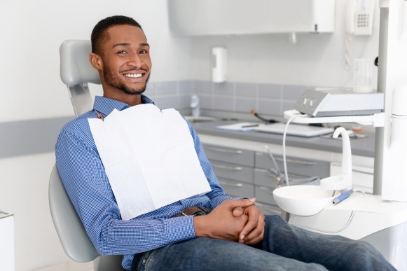 A smiling patient sitting in a Dallas dental office chair, waiting for a dental examination or procedure.
