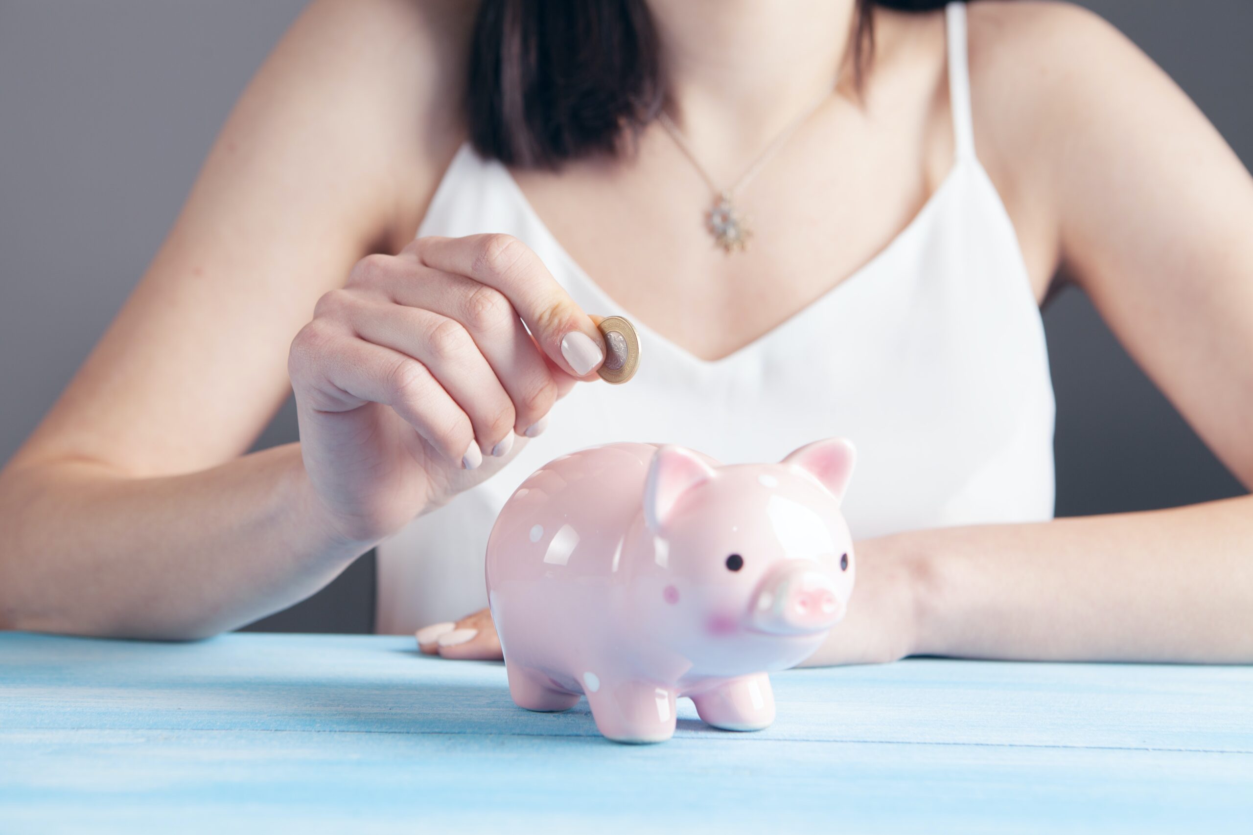 Woman inserting a coin into a piggy bank at a dental office.