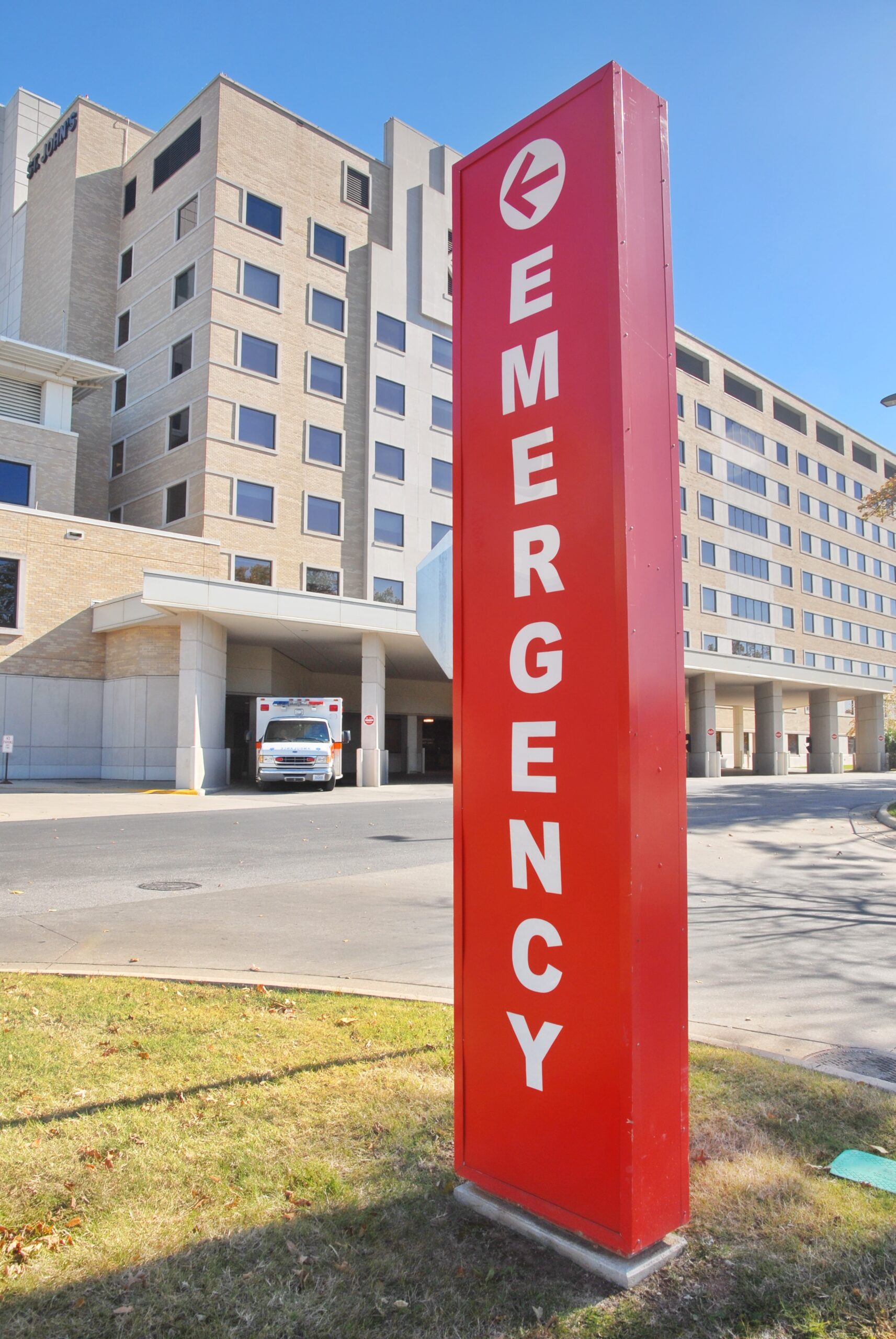Red emergency sign outside a hospital with an ambulance in the background, indicating the location of a Dallas dentist.