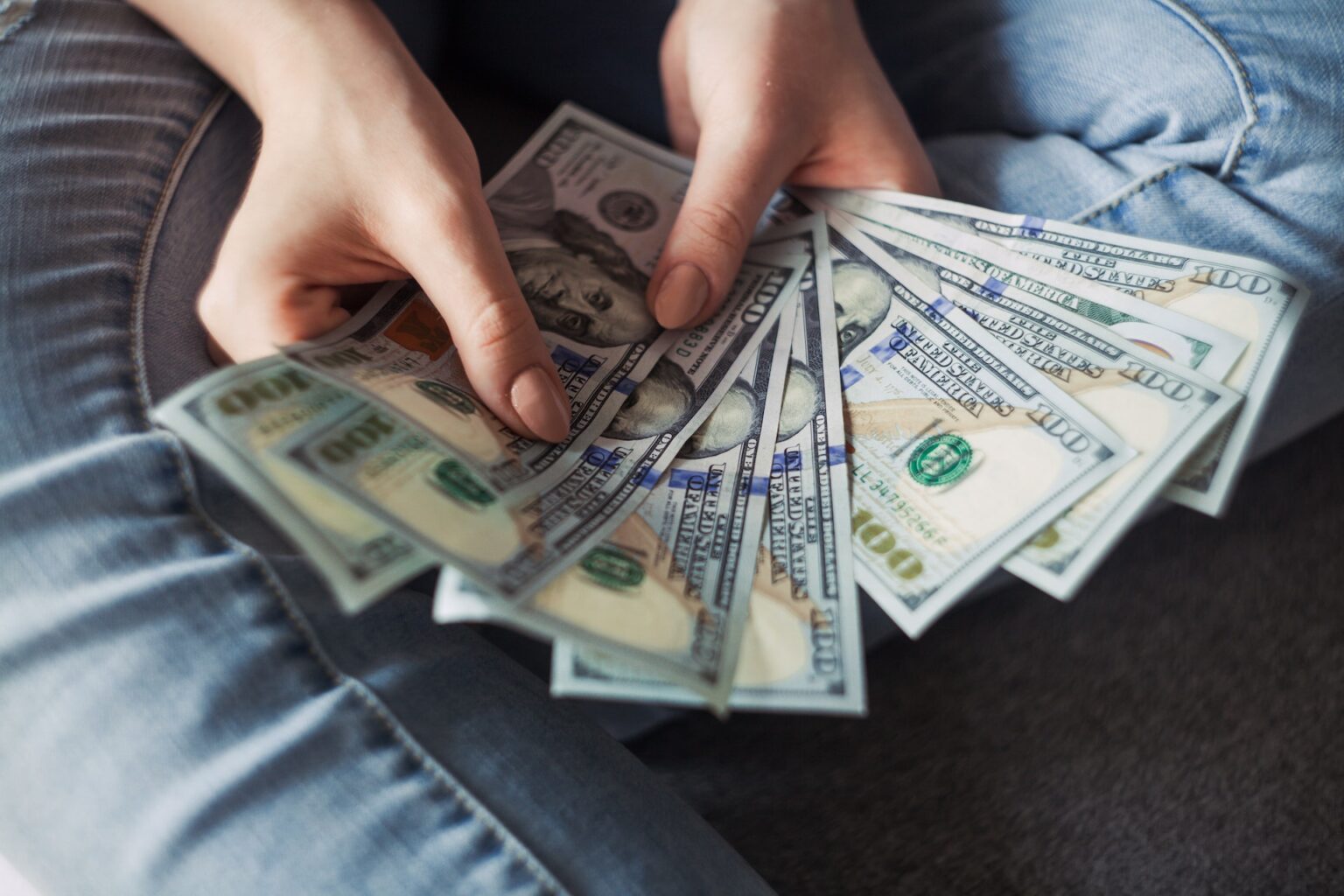 Person holding a fan of US dollar bills saved from visiting an affordable Dallas dentist.