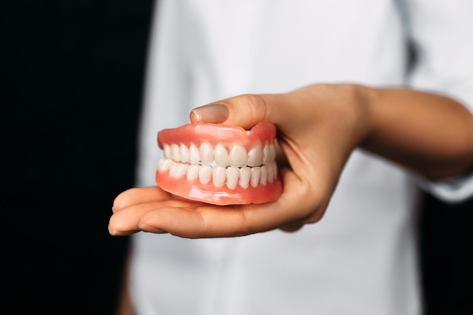 A person presenting a model of human teeth on their open palm at a Dallas dental clinic.