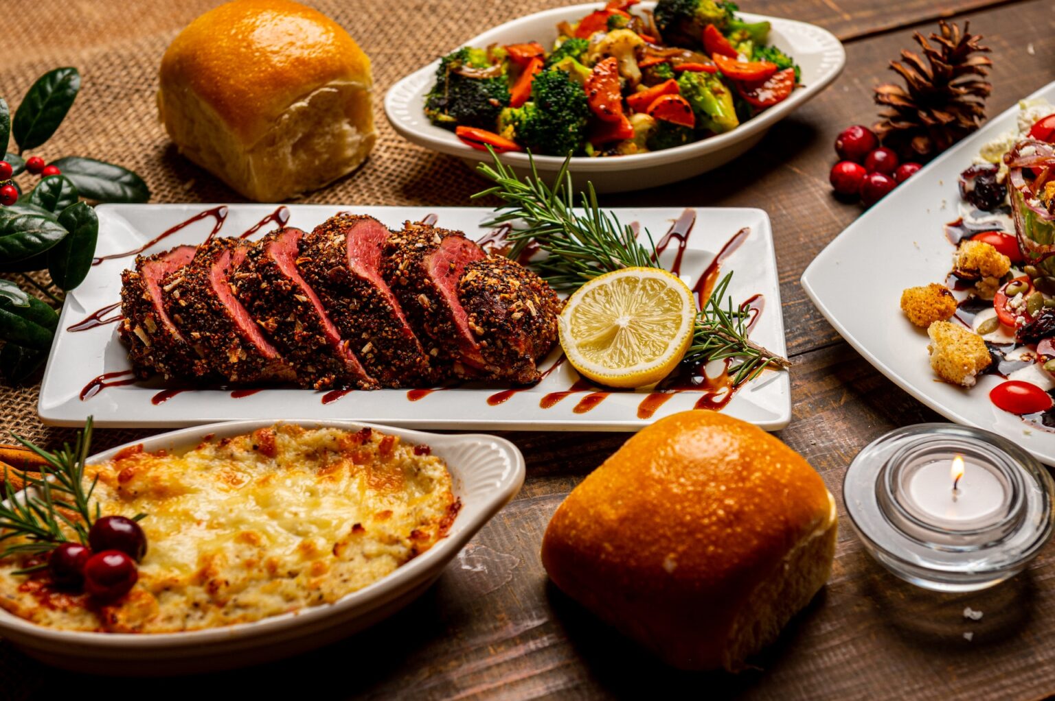 A festive dinner spread featuring sliced roast, various side dishes, and holiday decorations on a wooden table at a dental clinic.