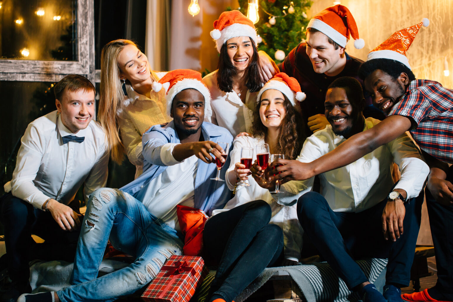 Group of friends at a Dallas dentist's dental office wearing Santa hats toasting with drinks at a Christmas party.