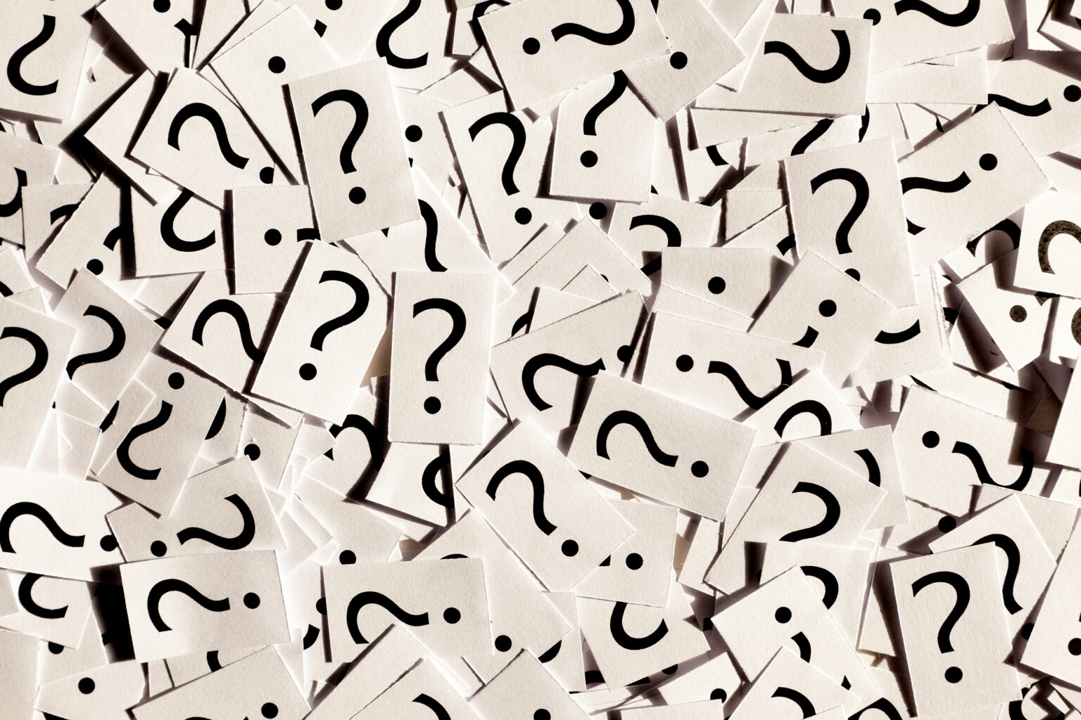 A scattered pile of paper cards, each featuring a printed question mark, scattered across the dental office reception desk.