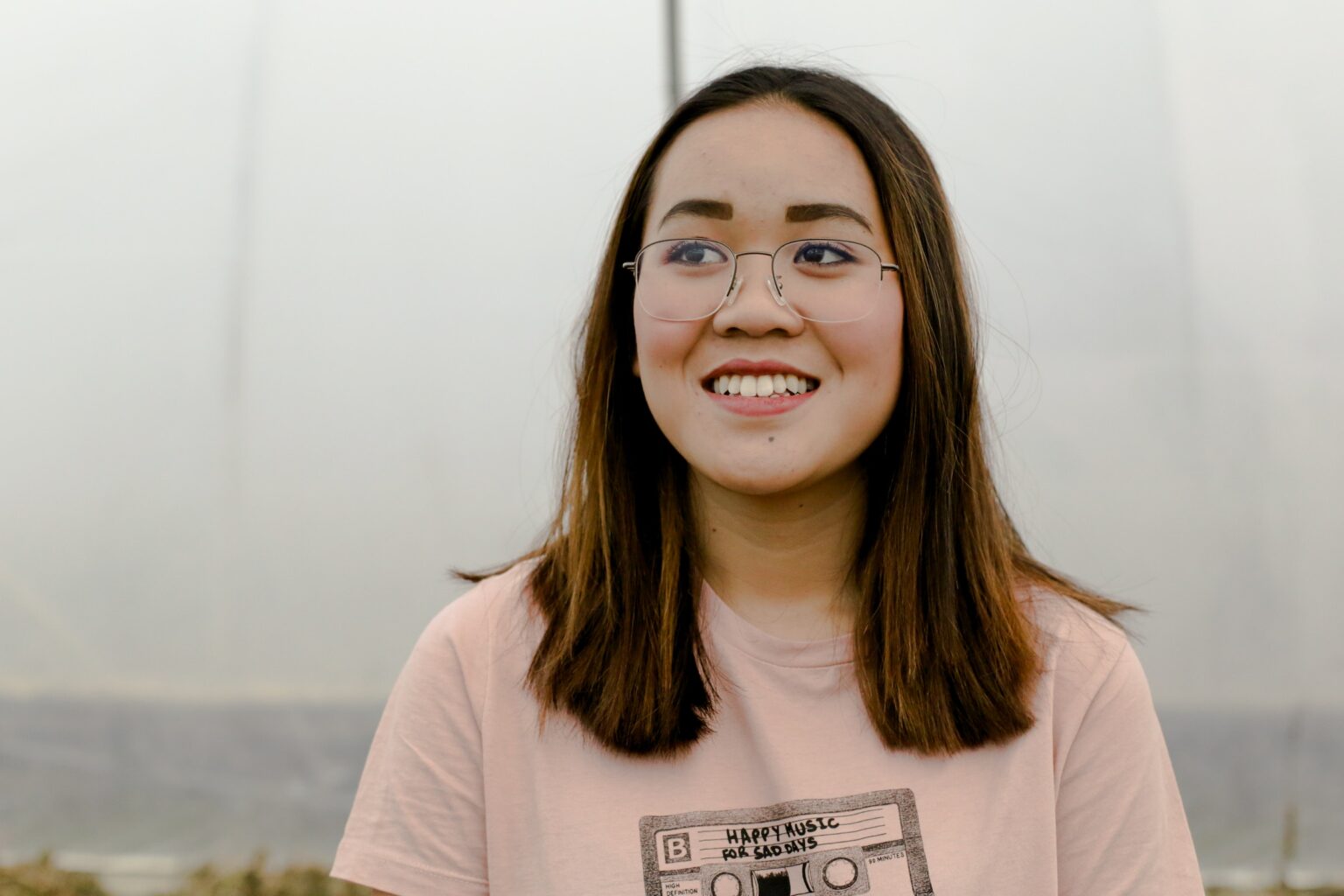 Young woman with glasses smiling outdoors after her visit to the Dallas dental office.