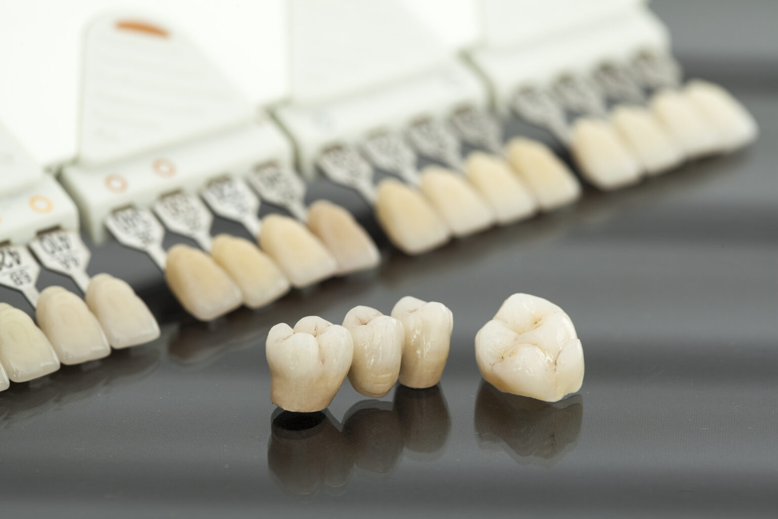 Dental crowns and shade guide on a reflective surface in an affordable Dallas dentist office.