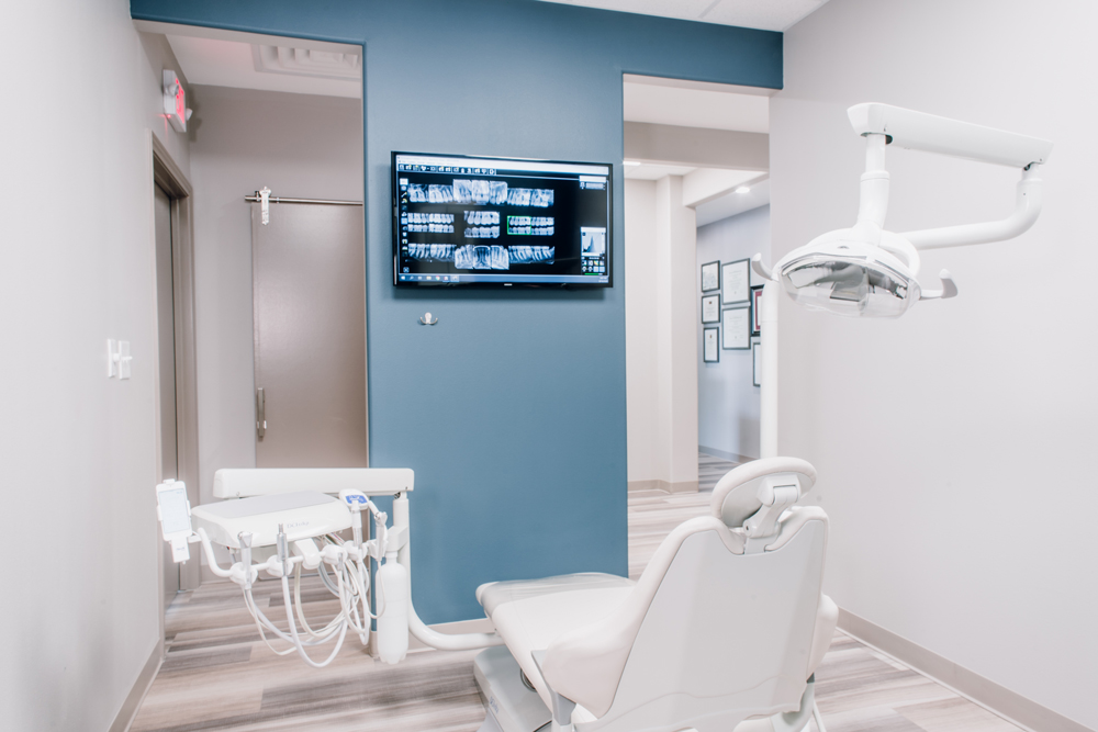 Modern dental clinic room in Dallas with an x-ray view display and an empty patient chair.
